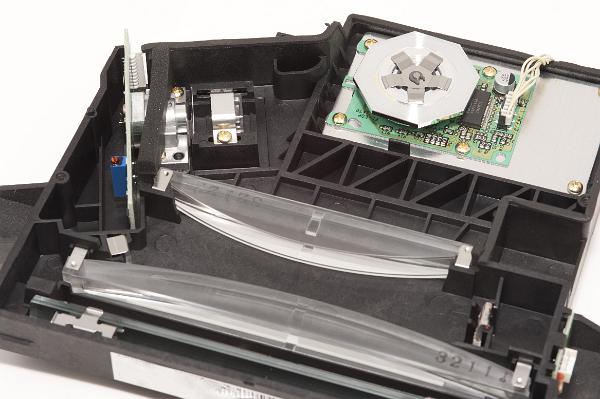 interor of a laser printer; the laser at the upper lens if focuesd trhough a mirror and them reflected from a spinning octagonal mirro upper centre; it is then reflected through a wide lens at the bottom of the picture onto a static charged drum