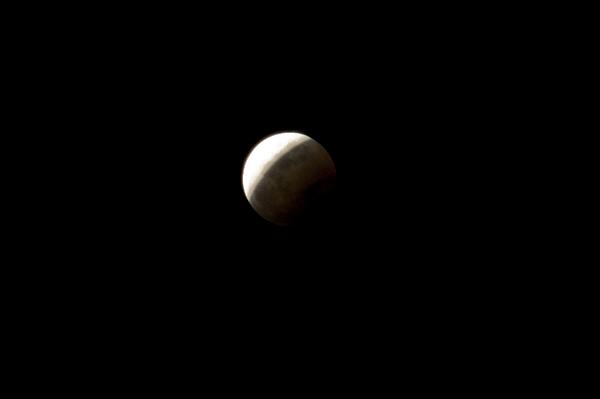 Half eclipsed moon and dark night sky A half eclipsed moon and dark night sky with copy space.