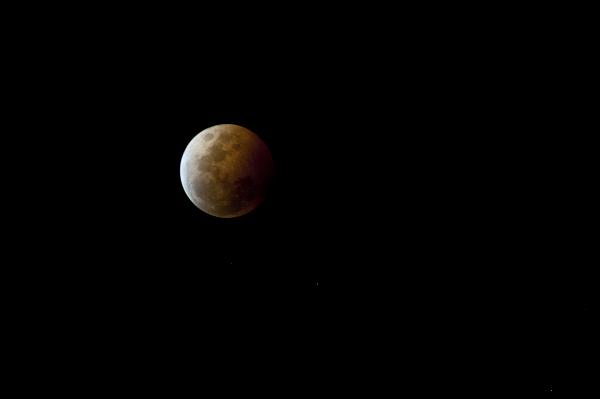 Partially eclipsed moon in a dark sky Partially eclipsed moon in a dark sky during a lunar eclipse cause by alignment with the earths shadow