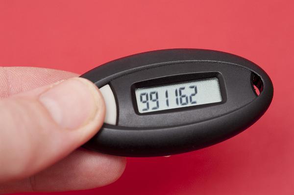 Digital device for generating an authentication code for security when banking held in a mans fingers over a red background