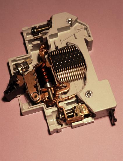 Miniature Circuit Breaker an MCB or resettable fuse circuit breaker. the circuit breaker trip in two ways to protect electrical wiring form overloads. a magnetic coil which mechanically trips the circuit breaker during a high current fault, and a bimetallic thermal overload which trips during a longer sustained but less significant overload. The matrix of metal bars on the right are a spark arrester, which uses the magnetic field from the coil to drag the spark away from the main contact seen at the bottom (hook shaped element currently in the open position)