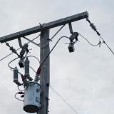 Cylindrical metal transformer mounted at the top on an wooden electricity pole in the distribution and supply network. such a transformer would convert 11kv or 6.6v down to 230 volts to commerical and domestic use
