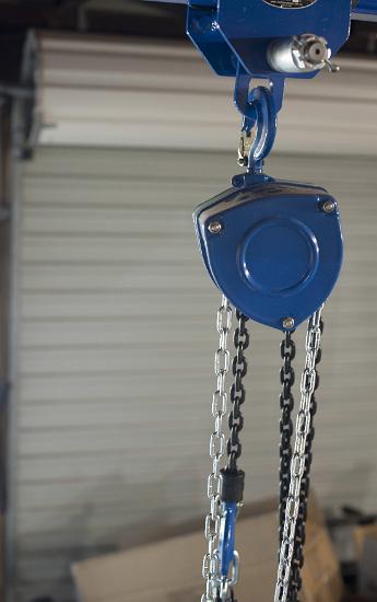 Industrial block and tackle in close up Industrial block and tackle in close up fitted with a steel chain for load lifting with lateral copy space