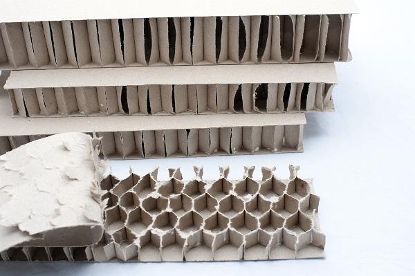 Honeycomb pattern for strength in cardboard View with the outer layer of a reinforced cardboard panel peeled back to expose the honeycomb structural pattern for strength of the inner layer