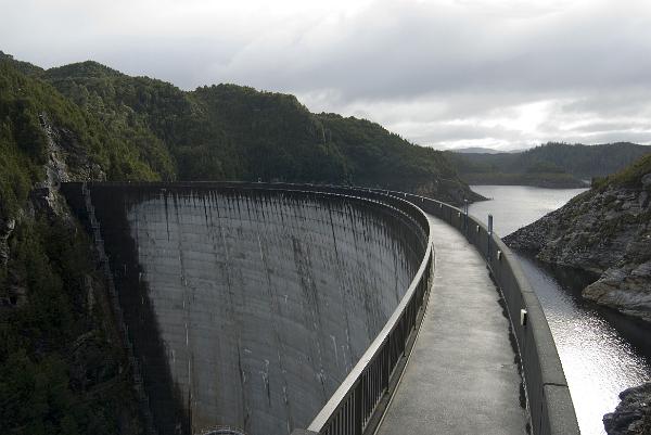 gordon dam wall a view from the footpath along to top of the gordon river dam, tasmania, the curve on the dam wall distributes the force of the water behind the dam sideways into the canyon wall