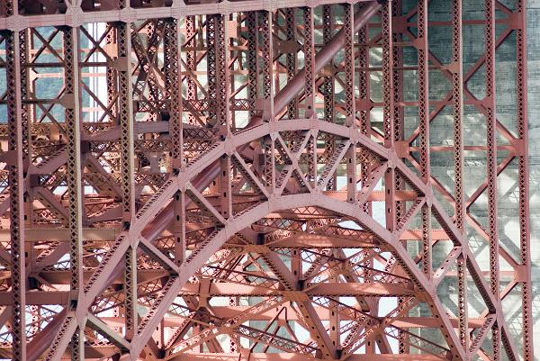 steel truss arch bridge details of the steel arch bridge structure at the southern end of the golden gate bridge, metal box trusses form an arch to distribute the load while the main suspension cable passes inbetween from borrom left to top right