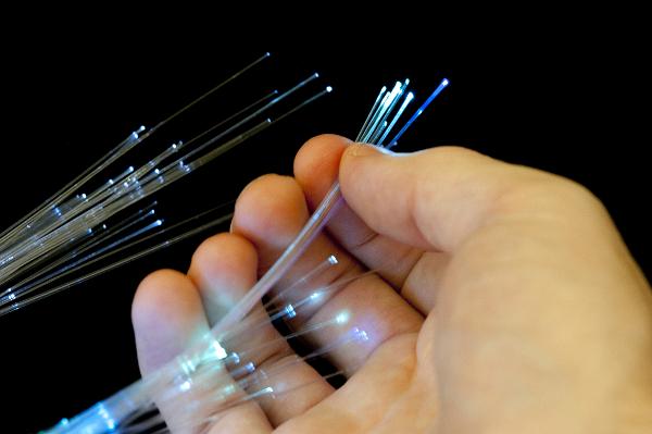Bundle of optical fibers held in hand Bundle of optical fibers held in hand up close on black background
