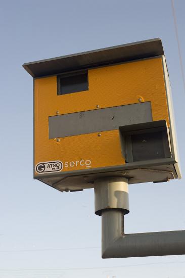 Yellow speed camera Yellow speed camera mounted on a pole overlooking a road to clock and photograph speeding motorists as they drive by in their cars, the camera uses a radar system the detect the speed of the motorist